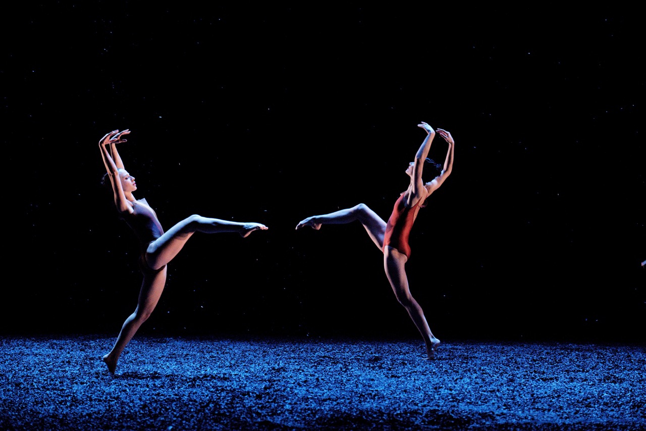 Dancers against a black background. Noise can be seen in the figures and background. 
