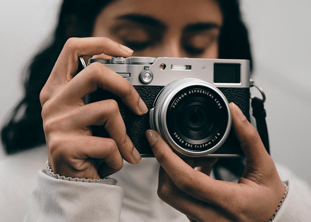 A woman holding a Fujifilm X100 VI camera